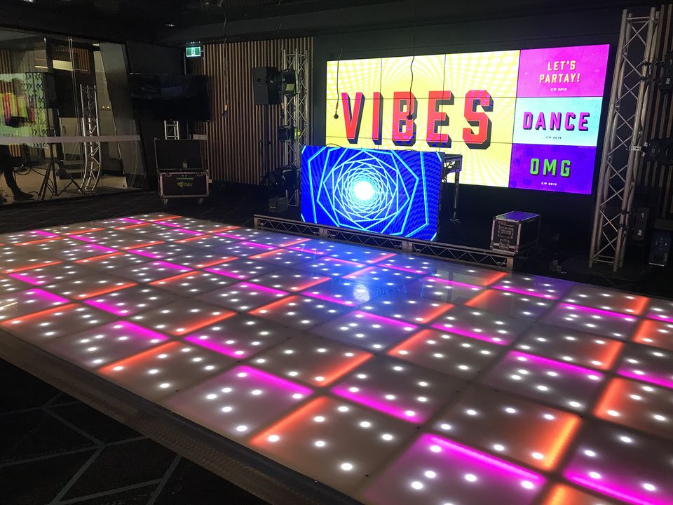 Colour LED dance floor in front of a stage with video screens