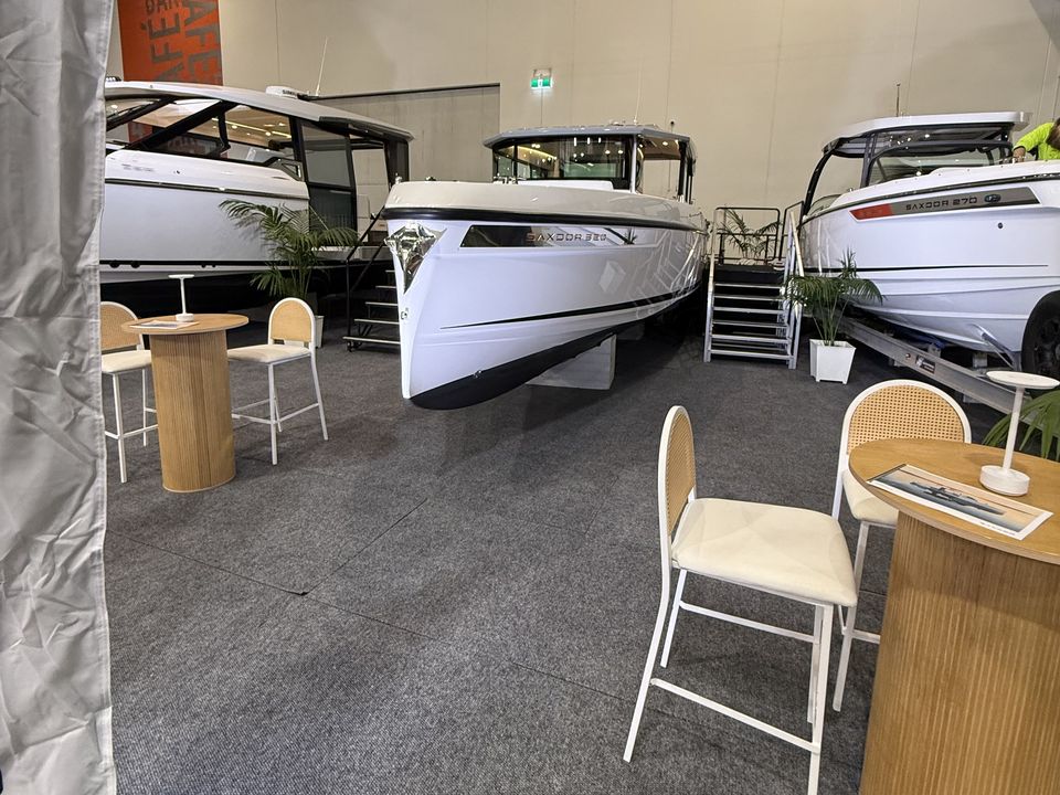 Boats on raised display stages with stairs, beside a lounge area with stools