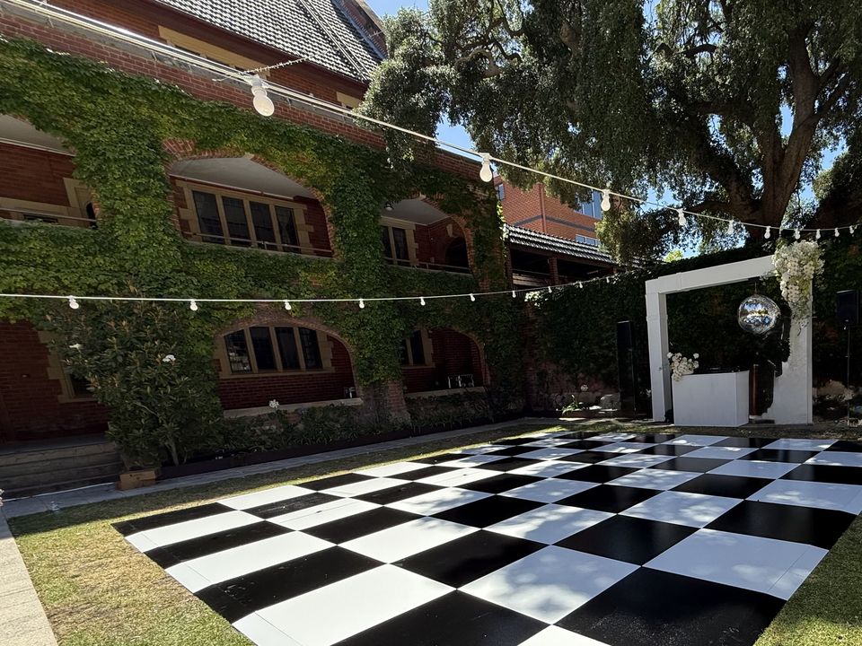 Festoon lights strung over a black and white dance floor in a courtyard
