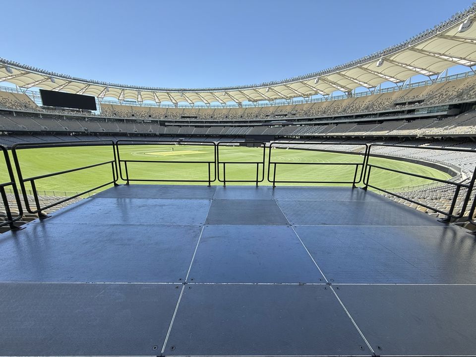 Railed black platform built over stadium seating, overlooking the field