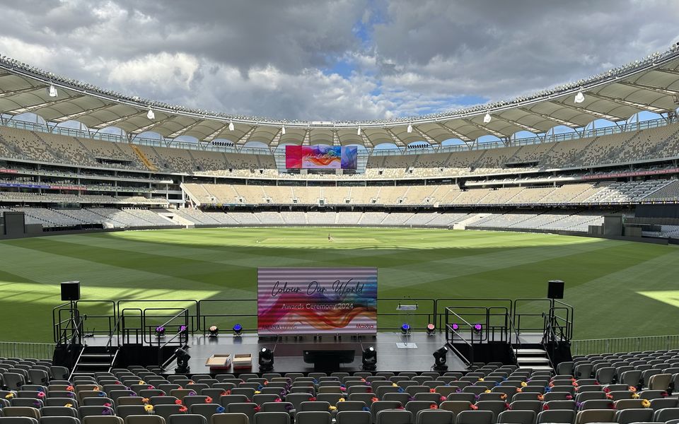 Event stage with stairs and handrails on a stadium field, facing rows of seating